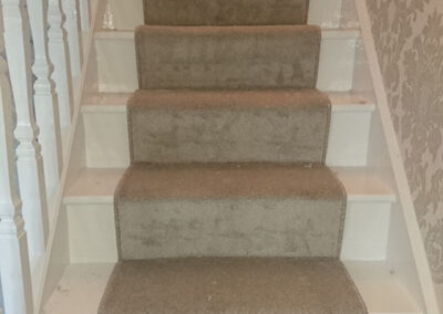 Beige carpet runner on on white stairs